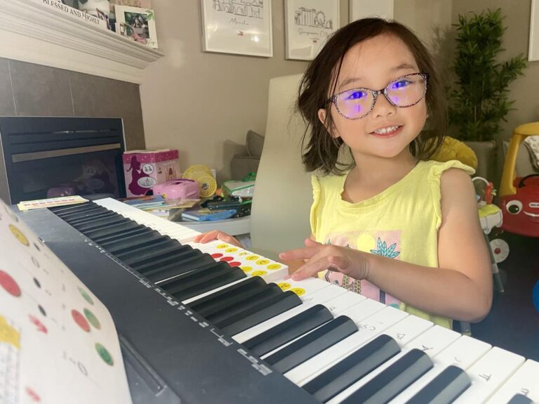 Harana Music Academy student learning how to play piano with the help of music teacher from Edmonton